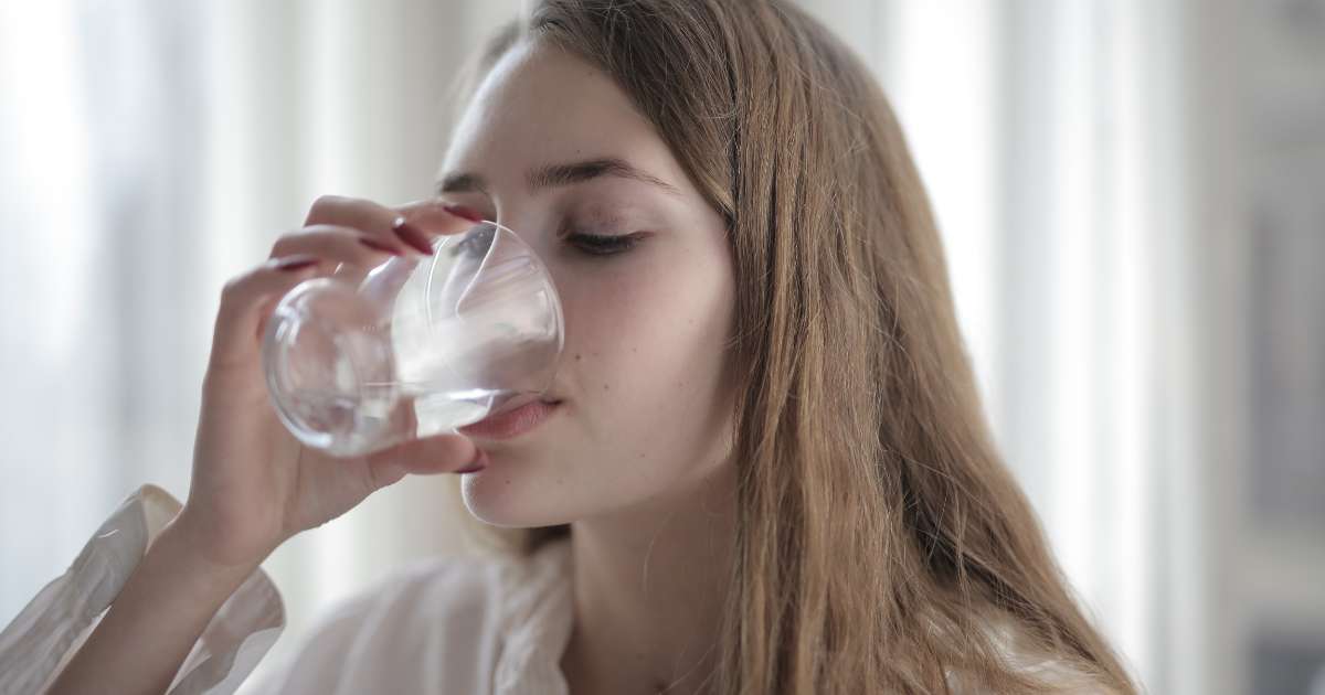 A woman who is drinking water for hydration.