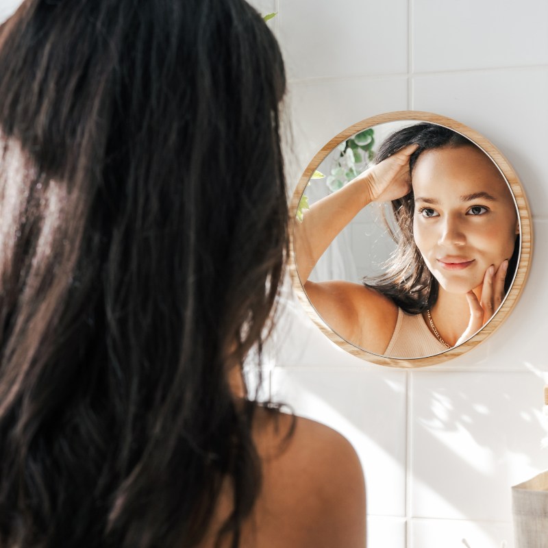 someone looking at their skin in the mirror